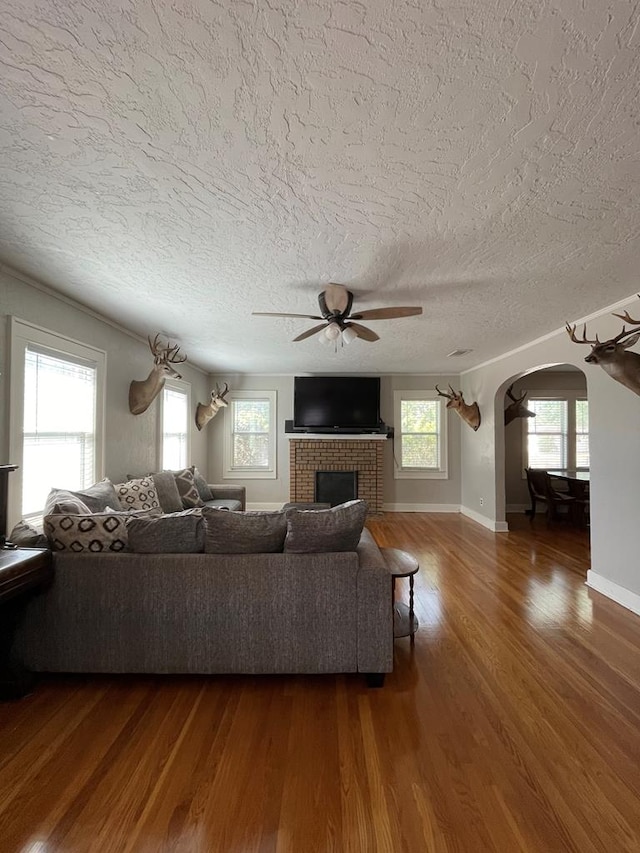 unfurnished living room featuring a fireplace, ceiling fan, wood-type flooring, and a textured ceiling