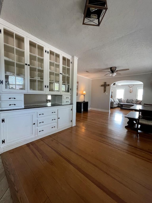 interior space featuring a textured ceiling, white cabinetry, ceiling fan, and dark wood-type flooring