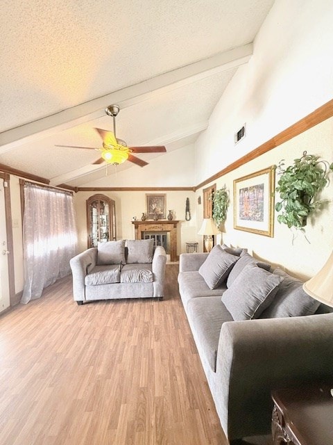 living area featuring visible vents, light wood-style flooring, a textured ceiling, ceiling fan, and vaulted ceiling with beams