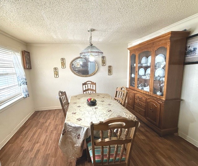 dining room with dark wood finished floors, ornamental molding, baseboards, and a textured ceiling