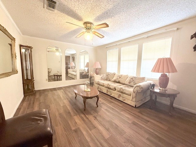 living room with visible vents, a ceiling fan, a textured ceiling, wood finished floors, and crown molding