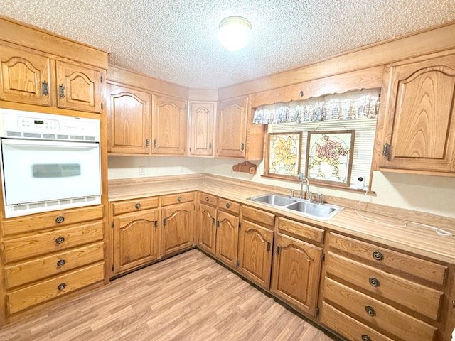 kitchen with a sink, light countertops, light wood-style floors, and oven