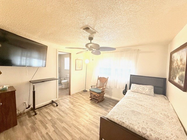 bedroom featuring multiple windows, wood finished floors, visible vents, and a textured ceiling