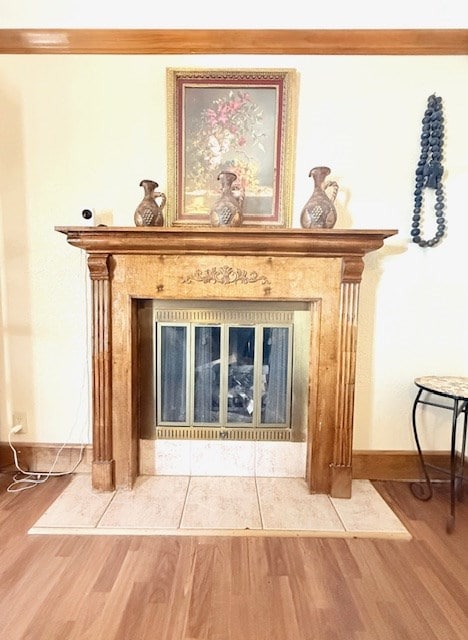 room details featuring a fireplace, baseboards, and wood finished floors