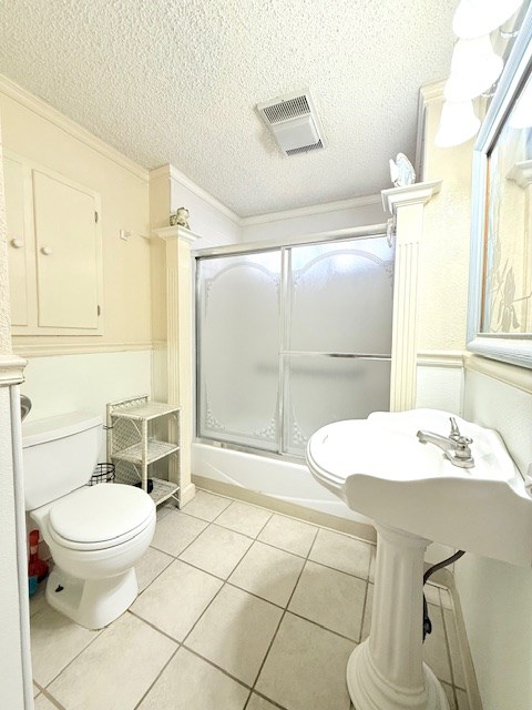 full bath with visible vents, toilet, ornamental molding, a textured ceiling, and tile patterned flooring