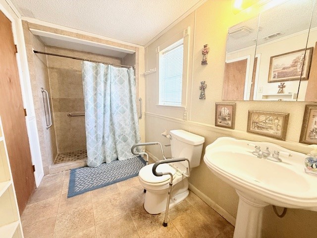 bathroom with a sink, a textured ceiling, a stall shower, and toilet