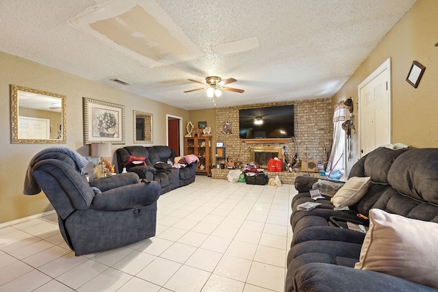 living room with ceiling fan, light tile patterned floors, a textured ceiling, and a brick fireplace