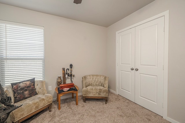 sitting room featuring baseboards, carpet floors, and a ceiling fan