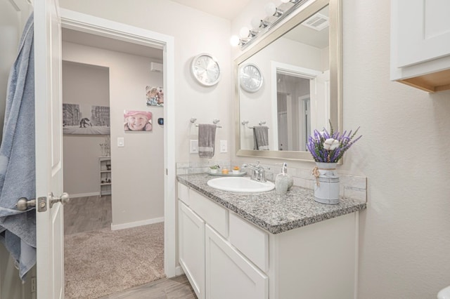 bathroom with vanity, wood finished floors, baseboards, and visible vents