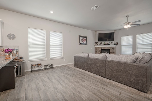 living area with visible vents, a ceiling fan, wood finished floors, a fireplace, and baseboards