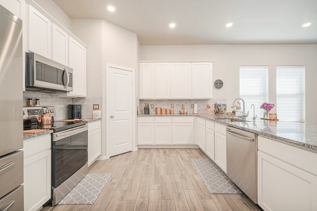 kitchen featuring tasteful backsplash, white cabinets, stainless steel appliances, and a sink