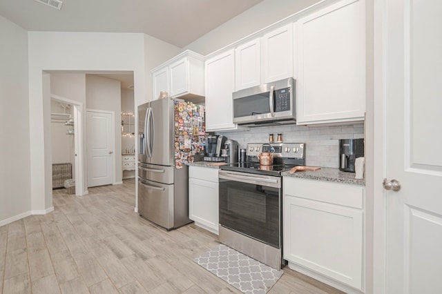 kitchen featuring stainless steel appliances, light wood finished floors, decorative backsplash, and white cabinetry