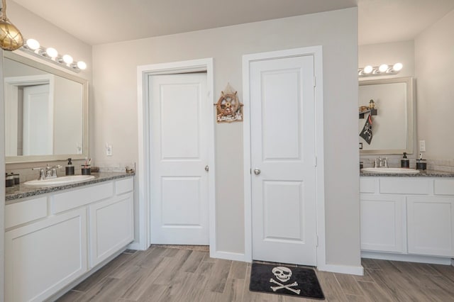 bathroom with two vanities, wood tiled floor, and a sink