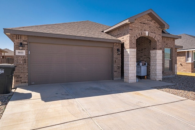 view of front of house with driveway, brick siding, and roof with shingles