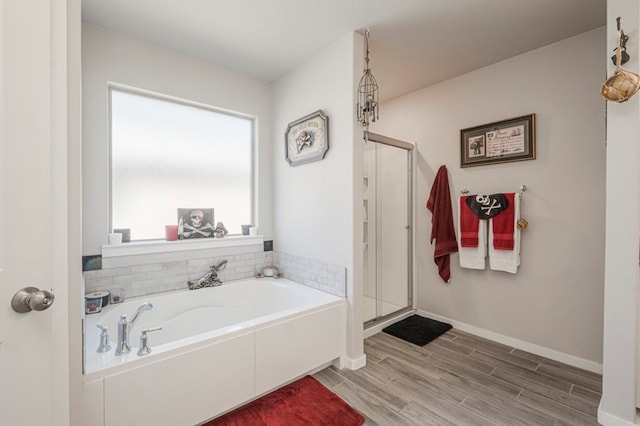 full bath with a bath, wood finished floors, a stall shower, and baseboards