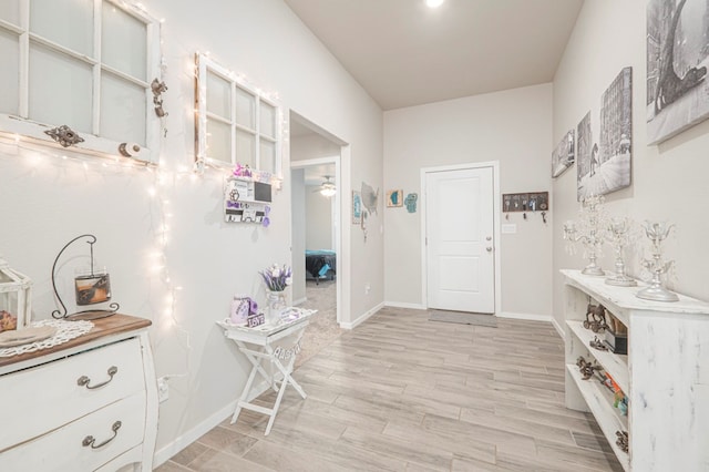 interior space featuring light wood-style floors, baseboards, and ceiling fan