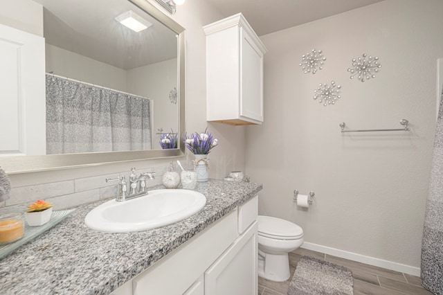 bathroom with wood finish floors, baseboards, toilet, a shower with shower curtain, and vanity