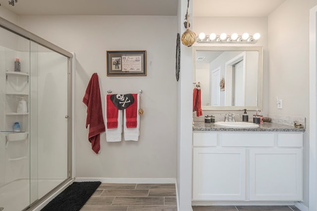 bathroom featuring a stall shower, vanity, baseboards, and wood tiled floor