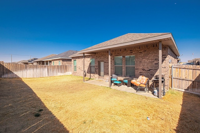 rear view of house with a patio, a fenced backyard, and brick siding