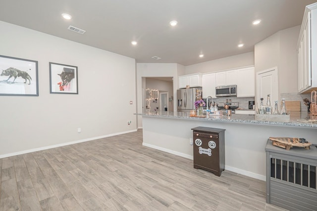 kitchen featuring tasteful backsplash, visible vents, light stone counters, appliances with stainless steel finishes, and white cabinetry