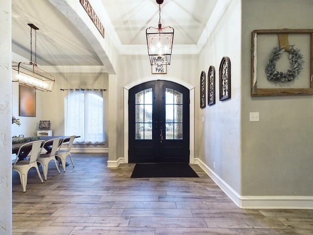 entrance foyer featuring a tray ceiling, crown molding, french doors, and hardwood / wood-style flooring