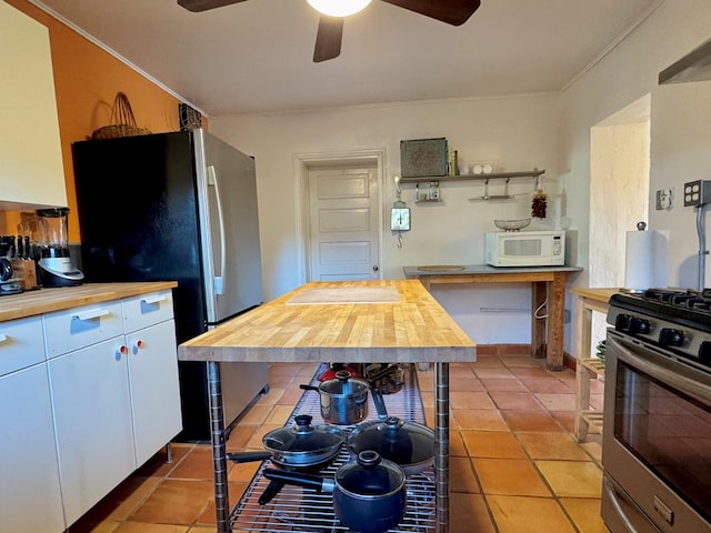 kitchen featuring wood counters, white cabinetry, light tile patterned floors, and appliances with stainless steel finishes