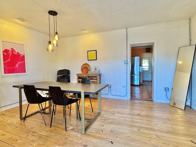 dining space featuring light hardwood / wood-style floors and a textured ceiling