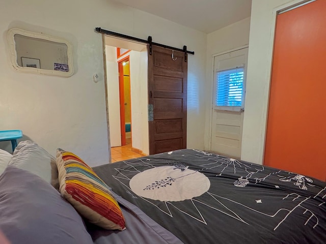 bedroom with a barn door and light tile patterned floors