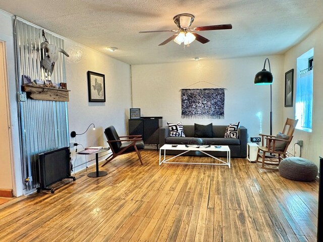 living room with hardwood / wood-style floors, a textured ceiling, and ceiling fan