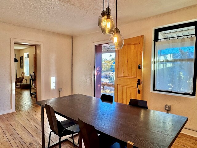 dining space with wood-type flooring and a textured ceiling