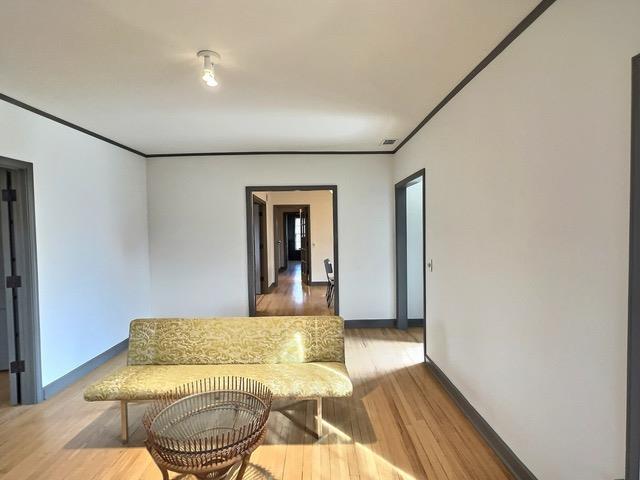 sitting room with wood-type flooring and crown molding