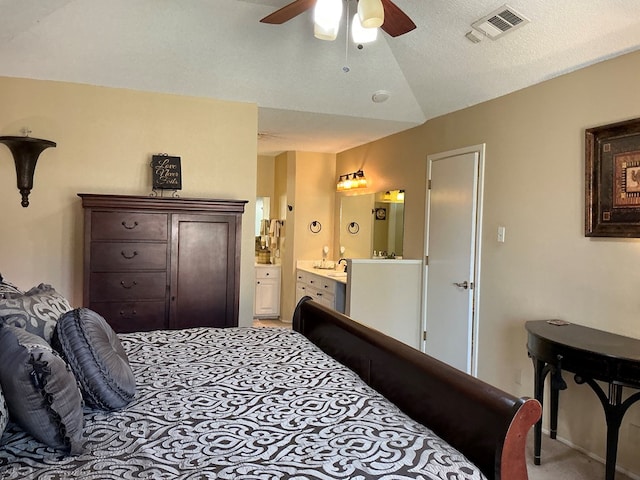 carpeted bedroom with visible vents, ceiling fan, vaulted ceiling, ensuite bathroom, and a textured ceiling