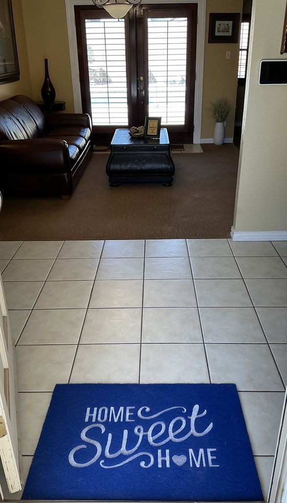 carpeted living area with tile patterned floors and baseboards