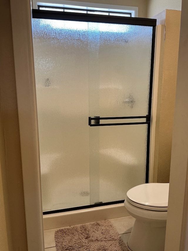 bathroom featuring a wealth of natural light, a shower stall, and tile patterned floors