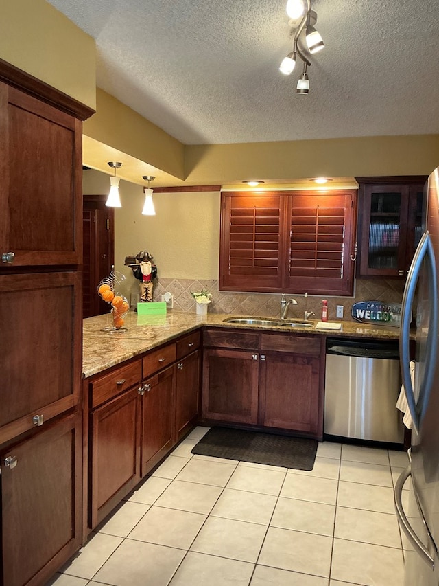 kitchen with light tile patterned floors, decorative backsplash, appliances with stainless steel finishes, a textured ceiling, and a sink