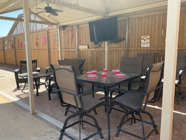 view of patio featuring outdoor dining space, ceiling fan, and fence