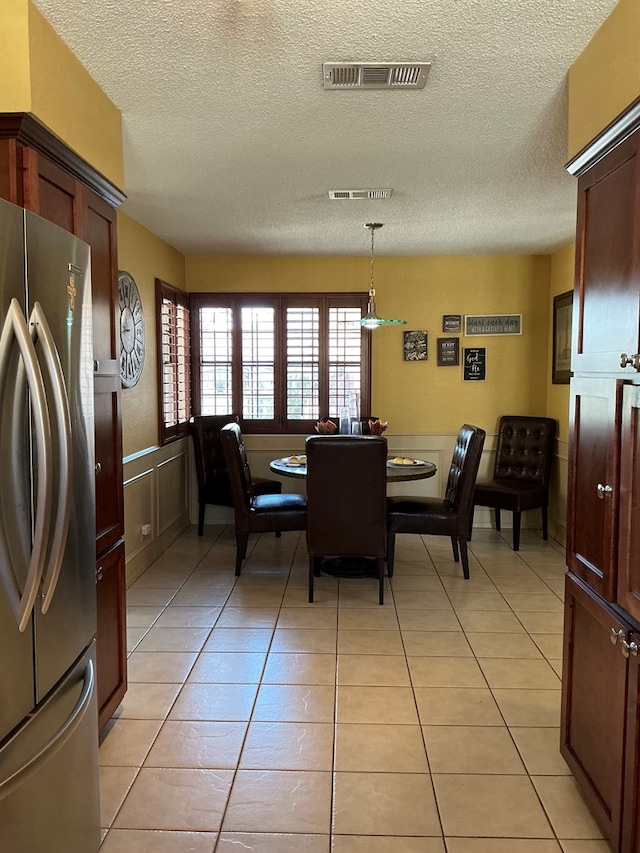 dining area with visible vents, a textured ceiling, and light tile patterned flooring