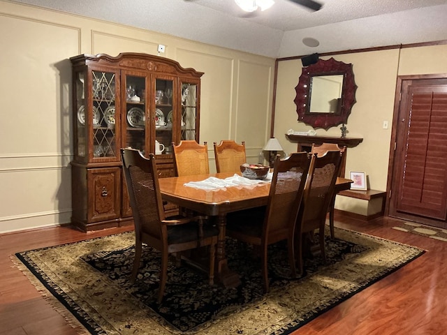 dining room with a textured ceiling, wood finished floors, a ceiling fan, and a decorative wall