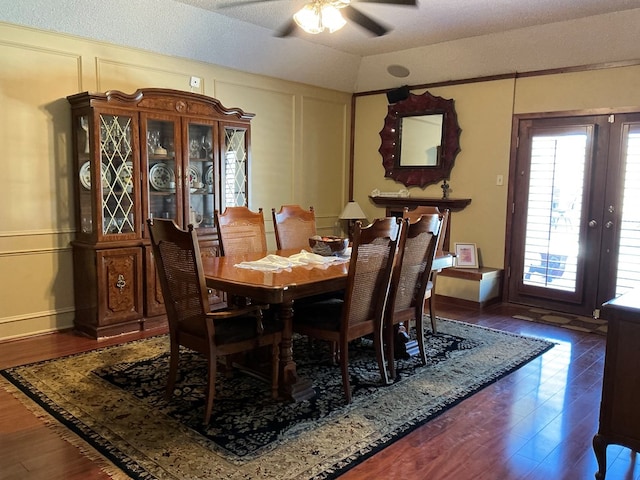 dining room with a decorative wall, french doors, a ceiling fan, and wood finished floors