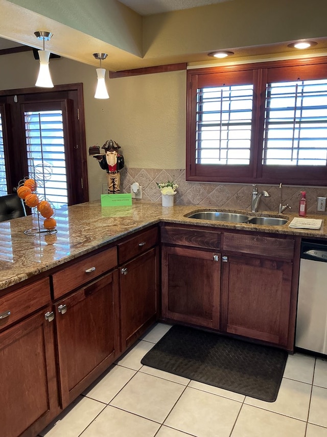 kitchen featuring a sink, stainless steel dishwasher, a wealth of natural light, and light tile patterned floors