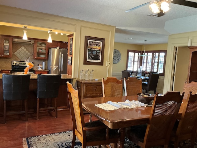 dining space featuring wood finished floors, visible vents, ceiling fan, a dry bar, and a decorative wall