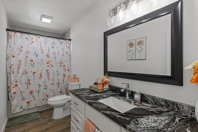 full bathroom with hardwood / wood-style flooring, vanity, shower / bath combination with curtain, a textured ceiling, and toilet