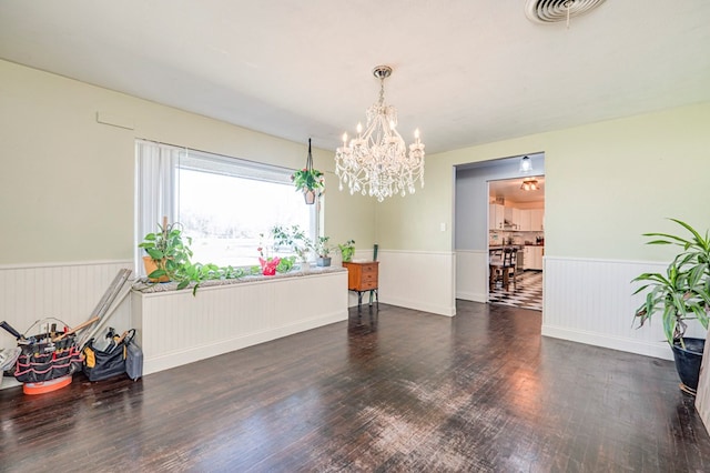 unfurnished room featuring dark wood-type flooring and a notable chandelier