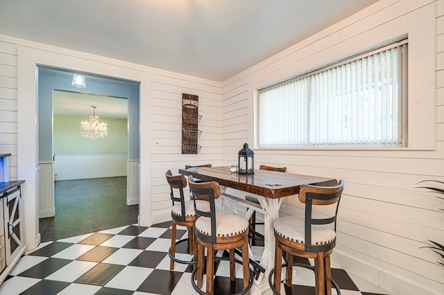 dining room featuring wooden walls and a notable chandelier