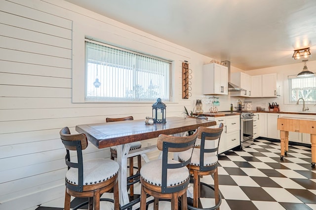 kitchen featuring white cabinetry, backsplash, a kitchen bar, electric stove, and wooden walls