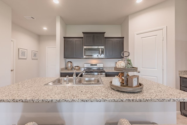 kitchen featuring appliances with stainless steel finishes, an island with sink, a breakfast bar area, and sink