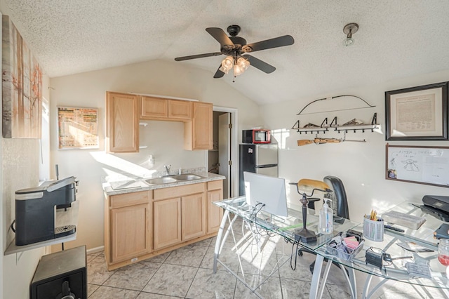 kitchen with light brown cabinetry, sink, vaulted ceiling, and stainless steel fridge