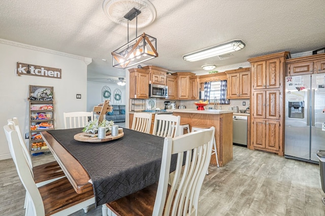 dining room featuring ornamental molding, a textured ceiling, and light wood-type flooring