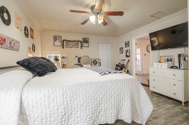 bedroom with ceiling fan, crown molding, wood-type flooring, and a textured ceiling