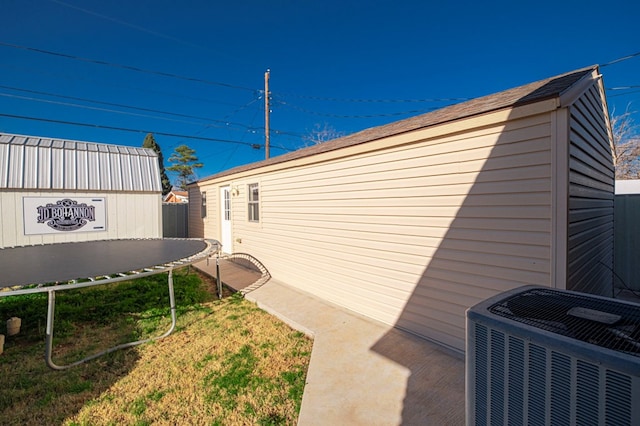 view of side of property with a trampoline and central air condition unit